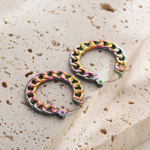 Detailed close-up of iridescent Cuban link chain hoop earrings on a stone surface