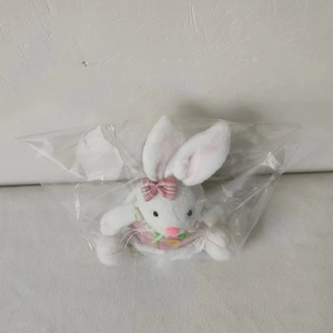 Close-up of a glowing Easter plush bunny with a pink bow in clear plastic packaging
