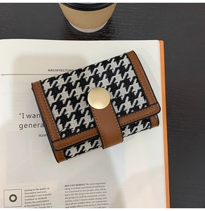 Houndstooth wallet with brown leather trim on book background with coffee cup