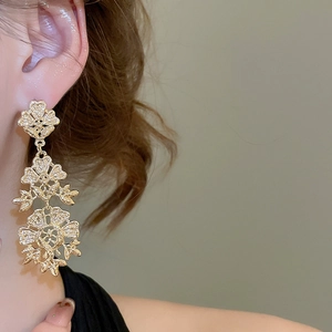 Detail of golden hollow flower tassel earrings showing baroque style texture and drop effect