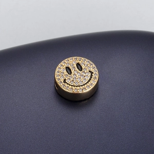 Detailed view of a gold smiley face bead with sparkling white crystals for DIY jewelry