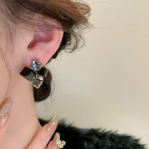 Close-up of elegant square crystal geometric stud earrings worn on a model's ear