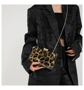 Detail of leopard print evening clutch bag with gold chain strap on black blazer