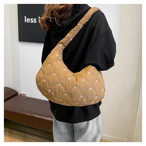 Detailaufnahme der braunen Stepptasche mit weißen Bogenschleifen und breitem Schultergurt