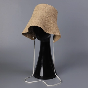 Detail of raffia straw hat with wavy brim and white scalloped ribbon ties