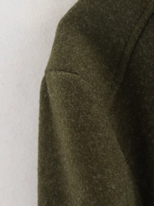 Gros plan de la veste en laine vert olive montrant la texture détaillée du tissu