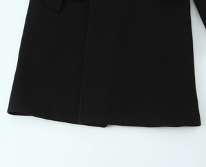 Close-up detail of smooth black coat fabric and professional stitching on the hemline