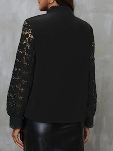 Detailed view of women's black top with elegant lace hollowed sleeves and standing collar