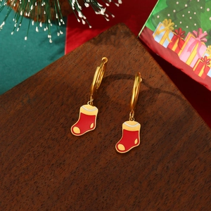 Nahaufnahme der 18K Gold Edelstahl-Ohrringe mit Weihnachtsstrumpf-Motiv auf Holzgrund