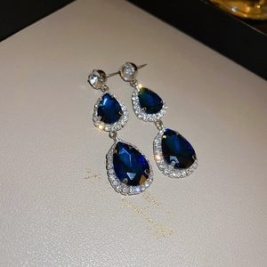 Detail shot of blue teardrop pendant earrings with white crystal halo on display