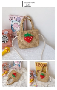 Detail of khaki straw woven bag with a cute red strawberry patch and crossbody strap