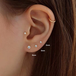 Close-up of 2mm, 3mm, and 4mm gold cubic zirconia stud earrings worn on the ear