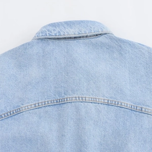 Detail of light blue denim romper showing collar stitching and back yoke texture