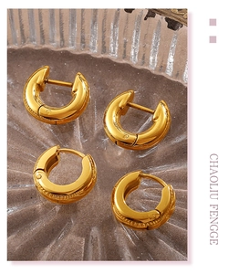 Macro shot of two pairs of thick gold-plated hoop earrings on a textured glass tray