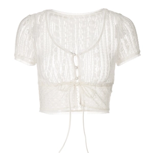 Dettaglio ravvicinato del cardigan corto in pizzo bianco con scollo a V e laccetti frontali