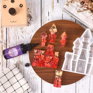 DIY kit showing a white silicone castle mold, red resin model, and UV resin on wood