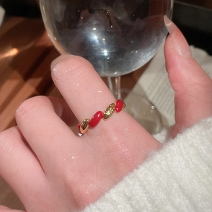 Close-up of a twisted gold-plated ring with red enamel inlay on a finger