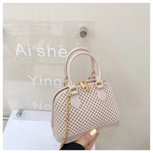 Detail of beige quilted jelly bag featuring gold chain strap and metallic hardware
