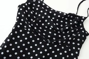 Detailed view of lightweight black chiffon fabric featuring a classic white polka dot pattern