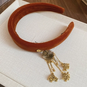 Close-up of caramel velvet headband with ethnic metal bells and tassel detailing