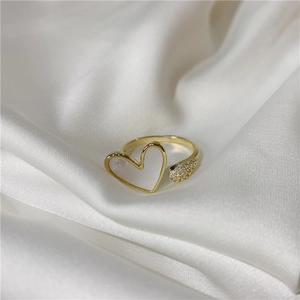 Detail of gold open ring featuring a white mother of pearl heart and diamond accents