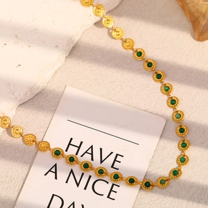 Detail of 18K gold plated beaded chain necklace with inlaid round green stones