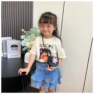 Detailed view of child model wearing a floral black crossbody bag with denim skirt outfit
