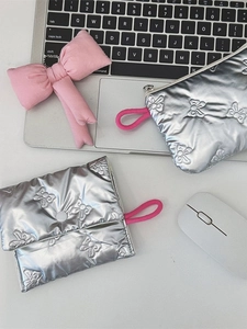 Silver quilted cosmetic bag with pink lanyard and butterfly pattern on white desk