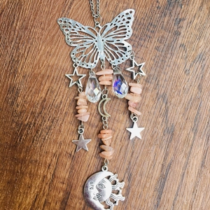 Detail of silver suncatcher featuring a hollow butterfly, crystal teardrop, and sun moon face