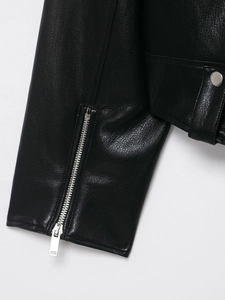 Detail of sleeve cuff with silver zipper and snap buttons on black faux leather biker jacket