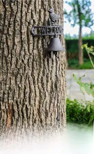 Detail of vintage cast iron welcome bell with bird statue on rustic tree bark