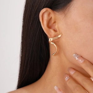 Detailed close-up of glossy gold spiral geometric earrings worn by a model