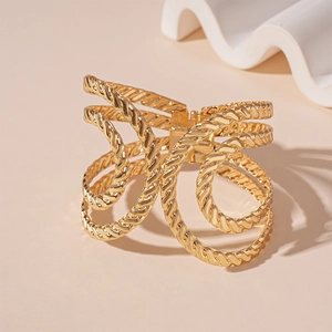 Macro detail of golden multi-layer twisted rope cuff bracelet with hinge closure