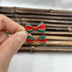 Close-up of small red and green striped Christmas bows with gold glitter and bells
