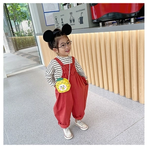 Close-up of cute yellow pineapple crossbody bag and red overalls on a child model