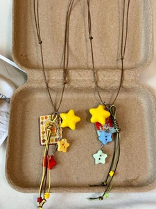 Detail of Y2K style acrylic star pendants on brown cord necklaces in a rustic gift box