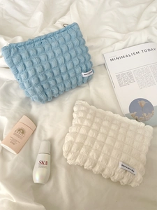 Close-up of candy-colored bubble texture cosmetic bags in light blue and beige fabric