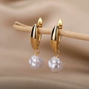 Detail of gold geometric earrings with white baroque pearls on a wooden branch