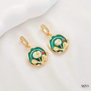 Detail of vintage gold earrings with green enamel floral patterns and zircon accents