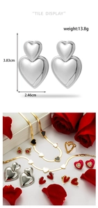 Detailed view of silver heart earrings and gold open ring on white leather jewelry box