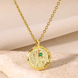 Macro shot of gold coin necklace with green stone and white zircon stars on sand stone