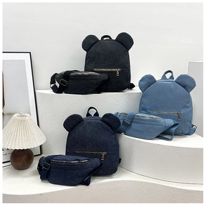 Detail view of denim canvas backpacks and waist bags with ear-shaped designs on display