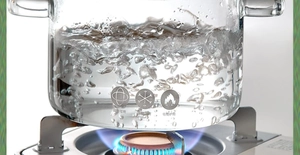 Close-up of a thick heat-resistant glass pot boiling water on a gas stove burner