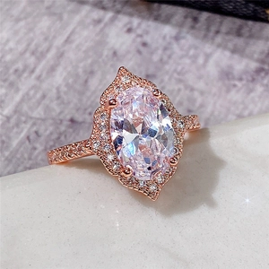 Macro shot of rose gold oval halo ring with sparkling cubic zirconia on stone base