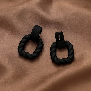 Detail shot of matte black twisted hoop earrings featuring vintage geometric texture