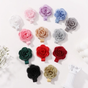 Handmade fabric rose hair clips in 13 colors arranged in heart shape on white background