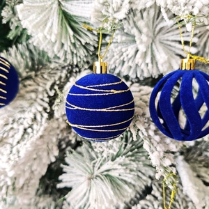 Gros plan de boules de Noël en velours bleu foncé avec rayures dorées sur branches