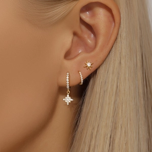 Detail of gold star opal earrings set with sparkling stones on model ear lobe