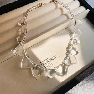 Irregular clear acrylic heart necklace with gold clasp in a beige velvet gift box