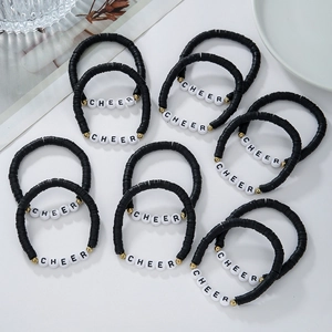 Detailed view of handmade CHEER friendship bracelets with black clay beads and gold accents